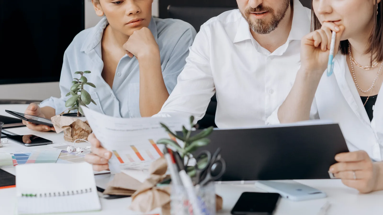 A small business team working together around a table with a laptop and tablet